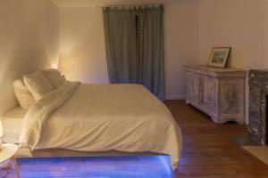 a bedroom with a white bed and a wooden dresser at L'Estagnole pour 2 personnes, jacuzzi, hammam in Estaing
