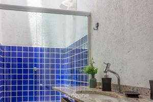 La salle de bains est pourvue de carrelage bleu et d'un lavabo avec un robinet. dans l'établissement VDA - Casas encantadoras e próximas à praia Camaragibe/AL, à Passo de Camarajibe