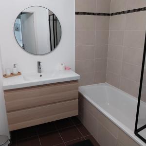 bagno con lavandino, vasca e specchio di Appartement cosy proche Disney a Ferrières-en-Brie