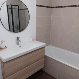bagno con lavandino, vasca e specchio di Appartement cosy proche Disney a Ferrières-en-Brie