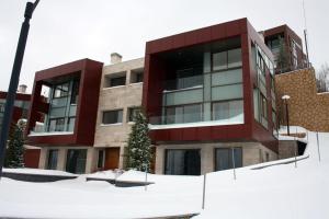 um edifício vermelho com neve em frente em LES Dunes De Faqra ( c duplex ) em Abū Mīzān