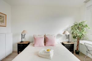 una camera da letto con un letto bianco e cuscini rosa di CHAMPS DE MARS - SUFFREN a Parigi