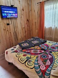 1 dormitorio con 1 cama con una manta colorida en Cabañas la Playa, en Isla Negra