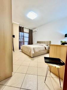 een slaapkamer met een bed en een stoel erin bij Chrigrey Holiday Apartments & Durres Beach in Durrës