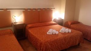 una camera d'albergo con due letti con scarpe bianche sul letto di Baglio Cudia Resort a Marsala