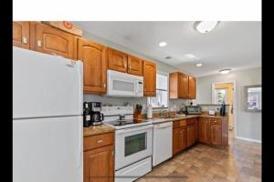 a kitchen with wooden cabinets and white appliances at Bobby's Beach Bungalow in Milford