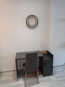 een bureau met een stoel en een klok aan een muur bij IN25G in Thessaloniki