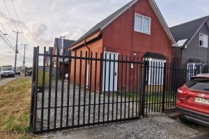 una casa roja con una valla delante en Alojamiento Casa completa en Puerto Montt en Puerto Montt