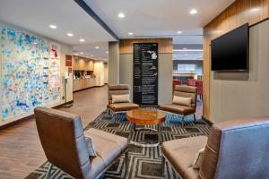TownePlace Suites by Marriott Detroit Belleville في بيلفيل: غرفة انتظار مع كراسي وطاولة وتلفزيون