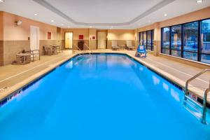 a swimming pool in a hotel lobby with a large window at TownePlace Suites by Marriott Detroit Belleville in Belleville