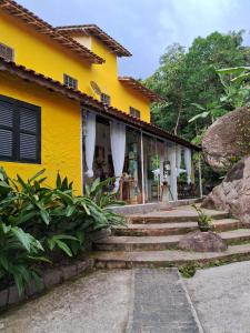 a yellow house with stairs in front of it at Pousada Familia Viva Trindade in Trindade