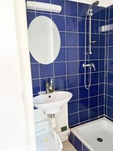 a blue tiled bathroom with a sink and a mirror at Studio Cosi Sxm in Marigot