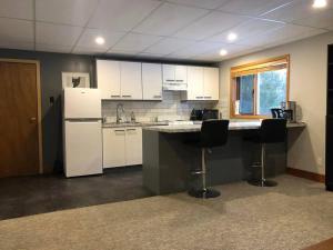 a kitchen with white appliances and a counter with two chairs at Basement Suite on a Goat Farm in Rossland