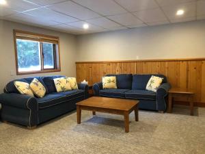 uma sala de estar com dois sofás azuis e uma mesa de centro em Basement Suite on a Goat Farm em Rossland