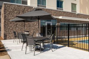 a table and chairs with an umbrella next to a pool at Fairfield by Marriott Inn & Suites Huntsville Redstone Gateway in Huntsville