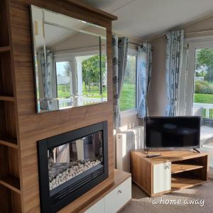 a living room with a fireplace and a tv at A HOME AWAY AT Tattershall country park in Tattershall