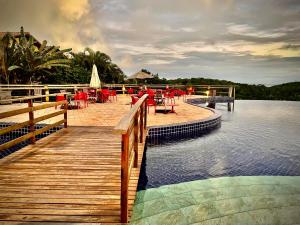 eine Holzbrücke über einen Wasserkörper mit Tischen und Stühlen in der Unterkunft Villas do Pratagy VIP in Maceió