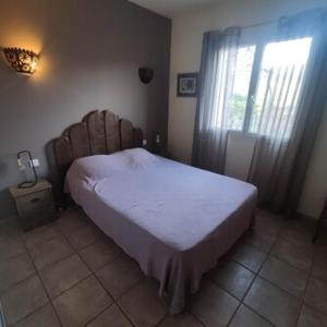 a bedroom with a bed and a window with a white sheets at Villa Sant Antone in Ghisonaccia