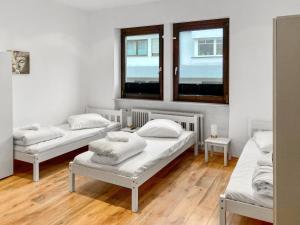 Cette chambre comprend trois lits et deux fenêtres. dans l'établissement CityChalet Monteur Apartments, à Sarrebruck