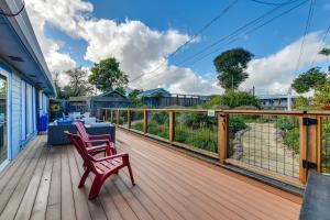 una terraza de madera con 2 sillas rojas. en Greenbrae Garden Cottage Near Beaches and Redwoods en Green Brae