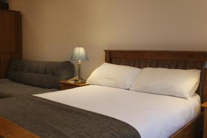 Un dormitorio con una cama, una silla y una lámpara. en Stylish flat in central Tenby & free parking, en Tenby