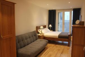 Un dormitorio con una cama y un sofá y una ventana. en Stylish flat in central Tenby & free parking, en Tenby