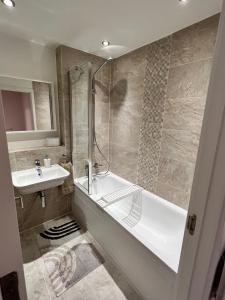 a bathroom with a bath tub and a sink at ORCHID S&N House in Bristol