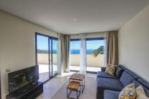 een woonkamer met een blauwe bank en grote ramen bij Los Monteros Penthouse with Panoramic Sea View in Marbella