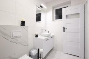 a white bathroom with a sink and a toilet at Apartamenty Różane in Laski +27 photos