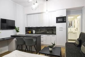 Apartamenty Różane في Laski: مطبخ وغرفة معيشة مع دواليب بيضاء