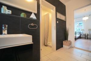 ein Badezimmer mit einem weißen Waschbecken und einer schwarzen Wand in der Unterkunft Ferienwohnung Möwe in zentraler Lage in Eckernförde