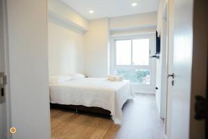 um quarto branco com uma cama e uma janela em Cookandmusicapartments Forvm Molas Lopez em Assunção