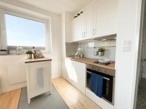 een keuken met witte kasten en een groot raam bij Ferienwohnung mit Meerblick - Kiek ut in Eckernförde