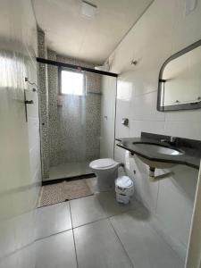 a bathroom with a shower and a toilet and a sink at Apartamento Praia do Morro com Churrasqueira, Cozinha Gourmet e Wifi in Guarapari