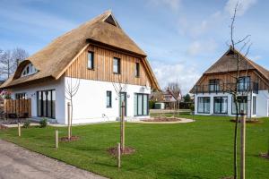 ein großes weißes Haus mit einem Strohdach in der Unterkunft Reethus Reethus 2 in Born