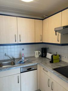 a kitchen with white cabinets and a sink at Bungalow Süüdstraat in Norderney +6 photos