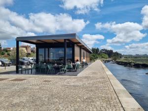 een gebouw met tafels en stoelen naast een rivier bij Passadiços da Ria in Aveiro