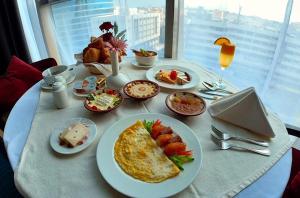 a table with plates of breakfast food on it at Hujra Hotel Tahlia Jeddah in Jeddah