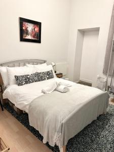 1 dormitorio con 1 cama con sábanas y almohadas blancas en C&E Apartment, en Edimburgo