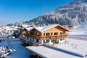 una casa en la nieve con una montaña en el fondo en M&M Appartements Brixental, en Westendorf
