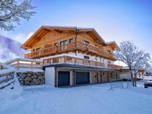 a large wooden house with a balcony in the snow at M&M Appartements Brixental in Westendorf
