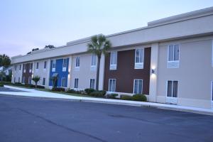 a large building with a palm tree in front of it at Best Western Pawleys Island in Pawleys Island