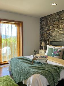 - une chambre avec un grand lit et un mur en pierre dans l'établissement Fontainha House & SPA, à Caldelas