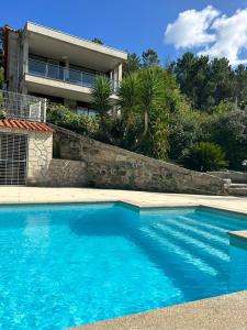 a blue swimming pool in front of a house at Fontainha House & SPA in Caldelas