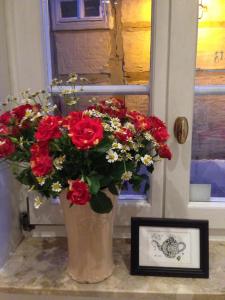 un jarrón lleno de flores rojas junto a una ventana en Hotel Domschatz, en Quedlinburg