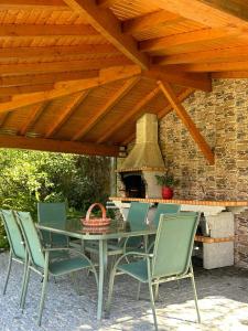 mesa y sillas bajo un techo de madera con fogones en Fontainha House & SPA en Caldelas