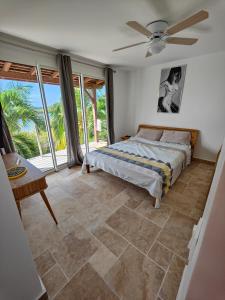 1 dormitorio con 1 cama y ventilador de techo en Villa Nadia - Prestige et Confort Absolu avec Vue Imprenable sur la Mer, en Le Diamant