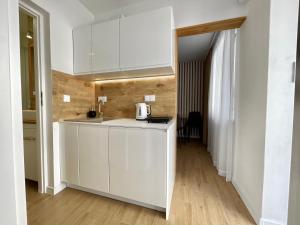 a kitchen with white cabinets and a wooden floor at BALi 22 in Ustronie Morskie