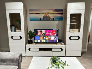 a living room with a tv on a white entertainment center at Luxury apartment in Slough FREE Parking near Heathrow, Legoland & Windsor Castle in Slough