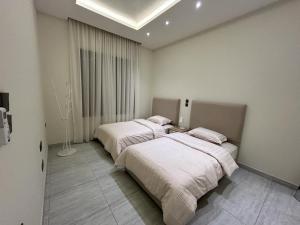two beds in a white room with a window at Smart luxury apartment 3bedrooms in Riyadh